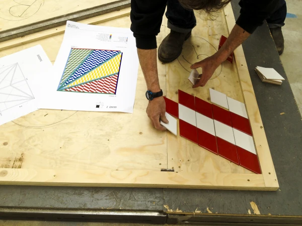 A triangular patterned tile panel being assembled in the workshop.