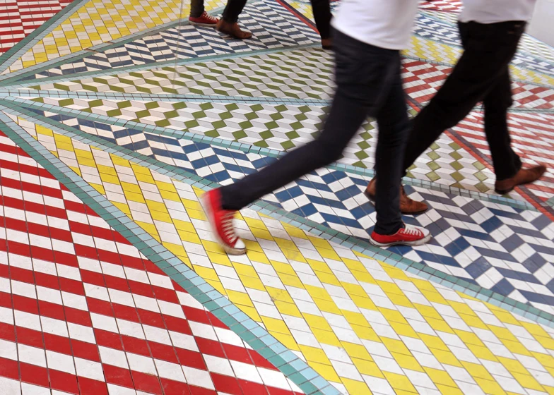 Visitors crossing the colourful geometric tile patterns.