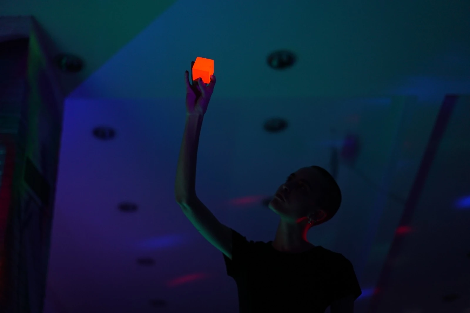 A figure holding a glowing red cube above their head
