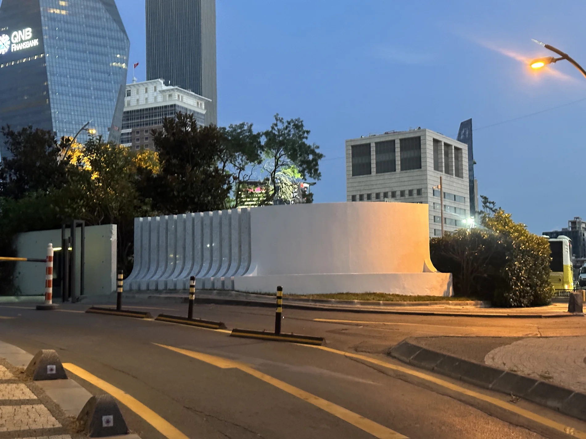 The repeated white fins and curved wall seen from the street at dusk