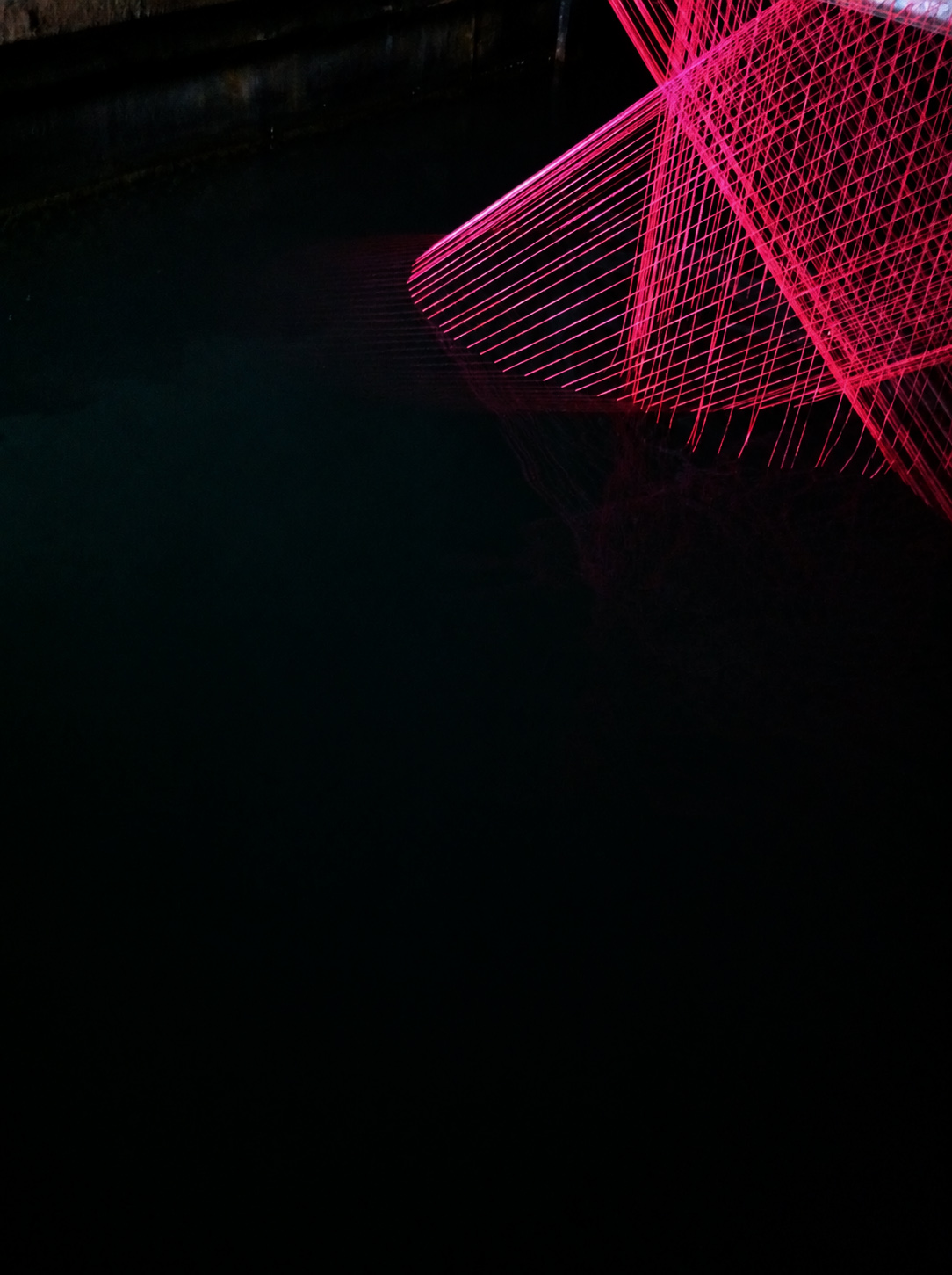 Coloured strings and their reflection on the dark water beneath the bridge
